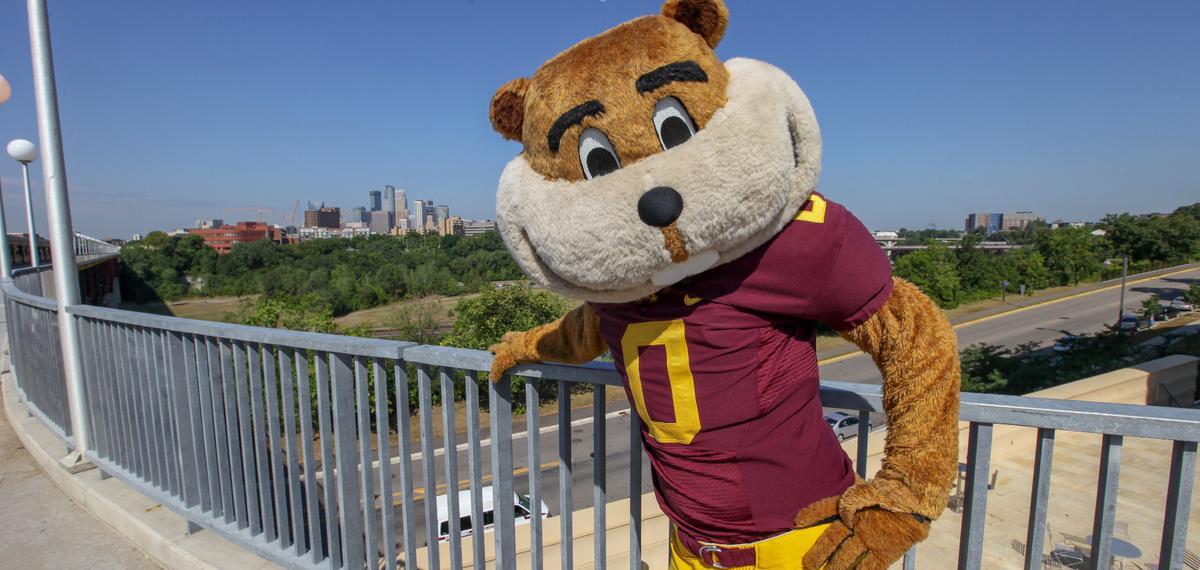 Goldy poses on a bridge in front of the city